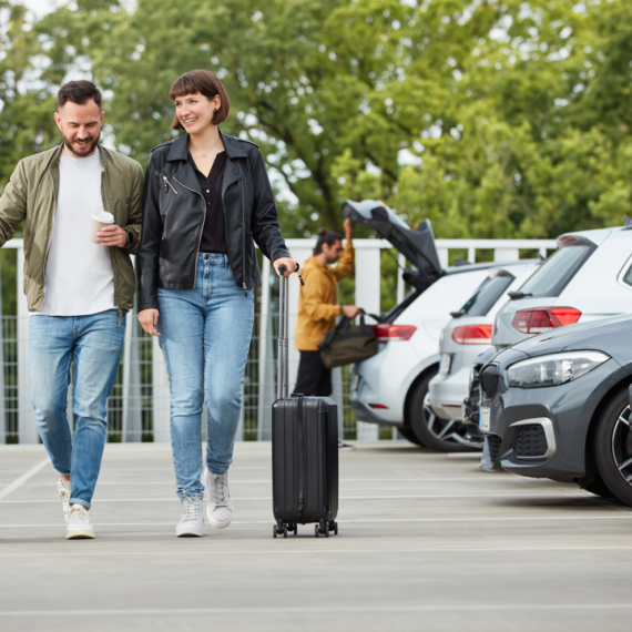 glückliche Parkkunden mit Koffern laufen über das Parkdeck 